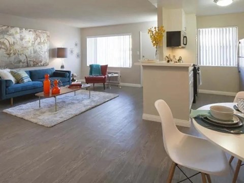A living room with a blue couch, a white chair, and a dining table with plates on it.