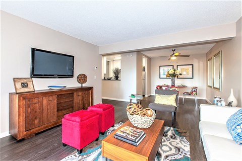 A living room with a television, a wooden cabinet, and a white couch.