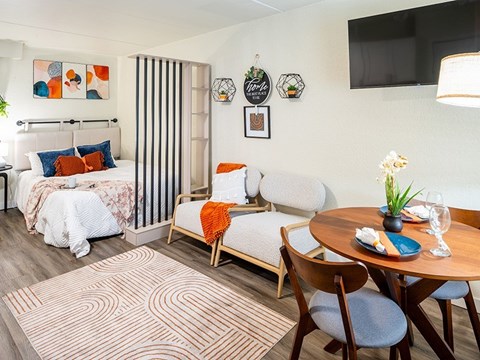 A bedroom with a bed, a chair, a table, and a television.