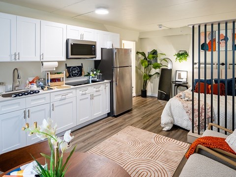A kitchen with white cabinets and a black fridge.
