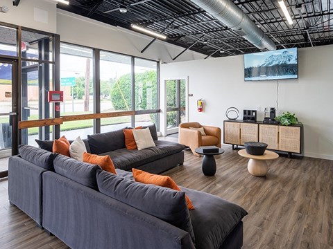 A living room with a grey couch and orange pillows.