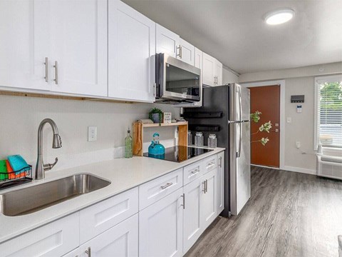 A kitchen with white cabinets and a black fridge.