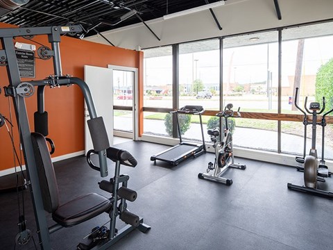 A gym with orange walls and a variety of exercise equipment.