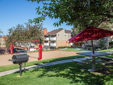 A picnic table is in the foreground of a grassy area with a red canopy and a sign that says "BARB WINDSOR".