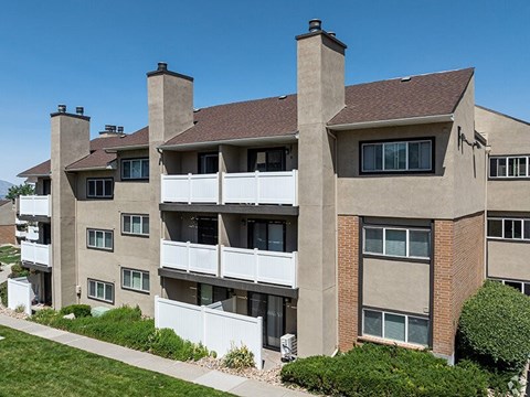 A large apartment building with a white fence in front.
