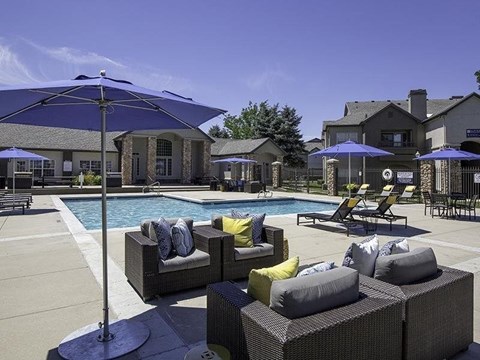 A poolside area with a large umbrella and a pool.