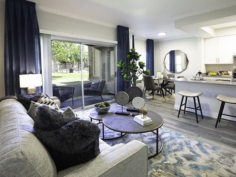 A living room with a grey couch and a round table with a plant on it.