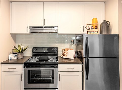 A modern kitchen with a black stove top and a black refrigerator.