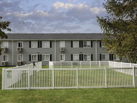 Apartment building with a white fence in front and a sign that says "Pet Area".