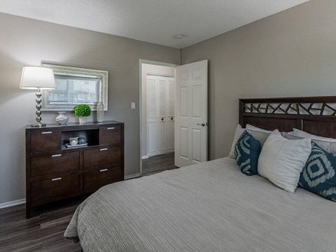 A bedroom with a bed, dresser, and window.