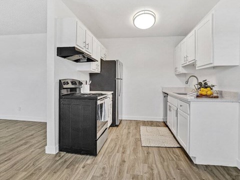 A kitchen with white cabinets and a black fridge.