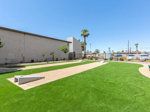 A large grassy area in front of a building with a bench.