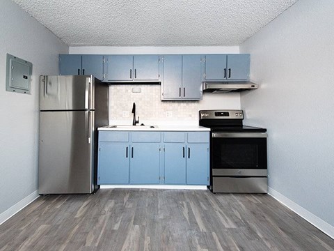 A kitchen with a refrigerator, oven, and cabinets.