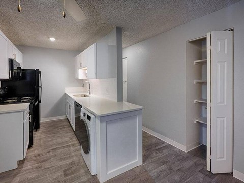 A kitchen with white cabinets and a black refrigerator.