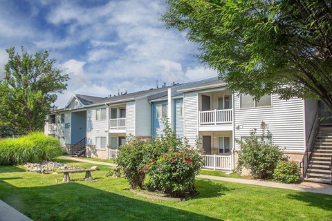A sunny day at a residential complex with a blue sky and greenery.