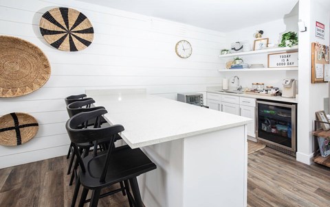 A kitchen with a white counter and black chairs.