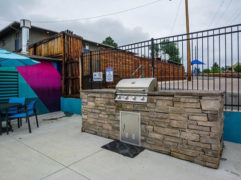 A BBQ grill is built into a stone wall.