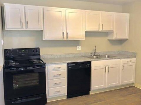 A kitchen with black appliances and white cabinets.