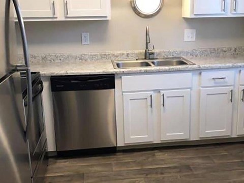 A kitchen with a stainless steel refrigerator and white cabinets.