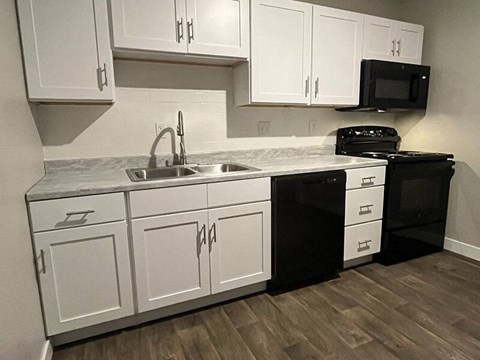 A kitchen with black appliances and white cabinets.