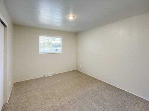 A room with a carpeted floor and a window.