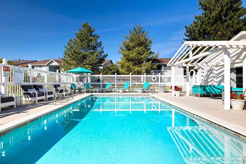 A large swimming pool with a white fence and a white pergola.