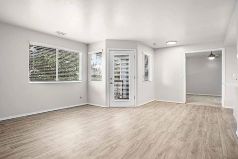 A room with wooden flooring and a window with blinds.