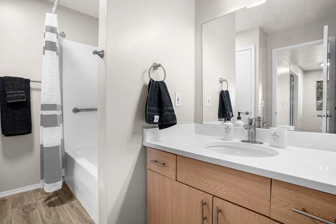A bathroom with a white sink and a white towel hanging on the shower rod.