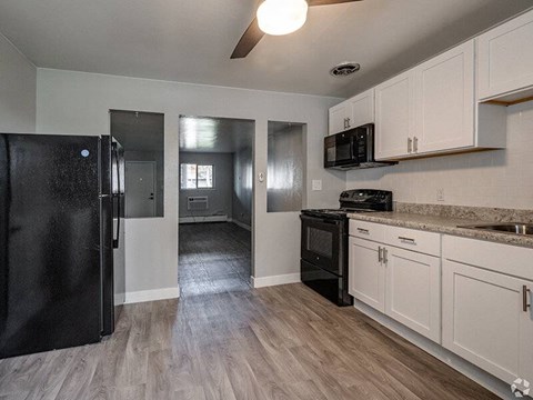 A kitchen with black appliances and white cabinets.