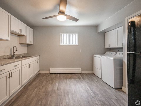 A kitchen with white cabinets and a black fridge.