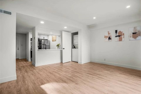 A spacious room with wooden flooring and white walls.