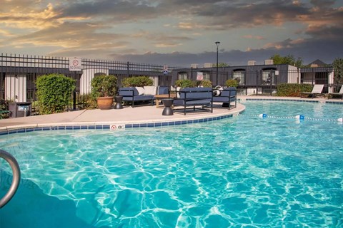 A pool with a blue tinted water and a sunset in the background.