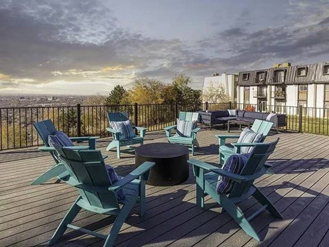 A wooden deck with blue chairs and a table.