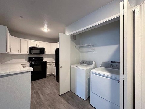 A small kitchen with a microwave, oven, and washing machine.