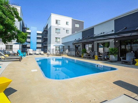 A large outdoor swimming pool with a yellow bench and a building in the background.