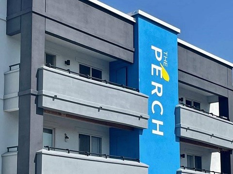 A blue and white sign on a building that says "The Perch".