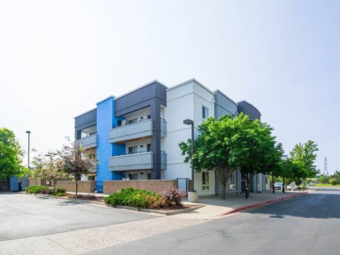 A modern multi-story building with a parking lot in front.