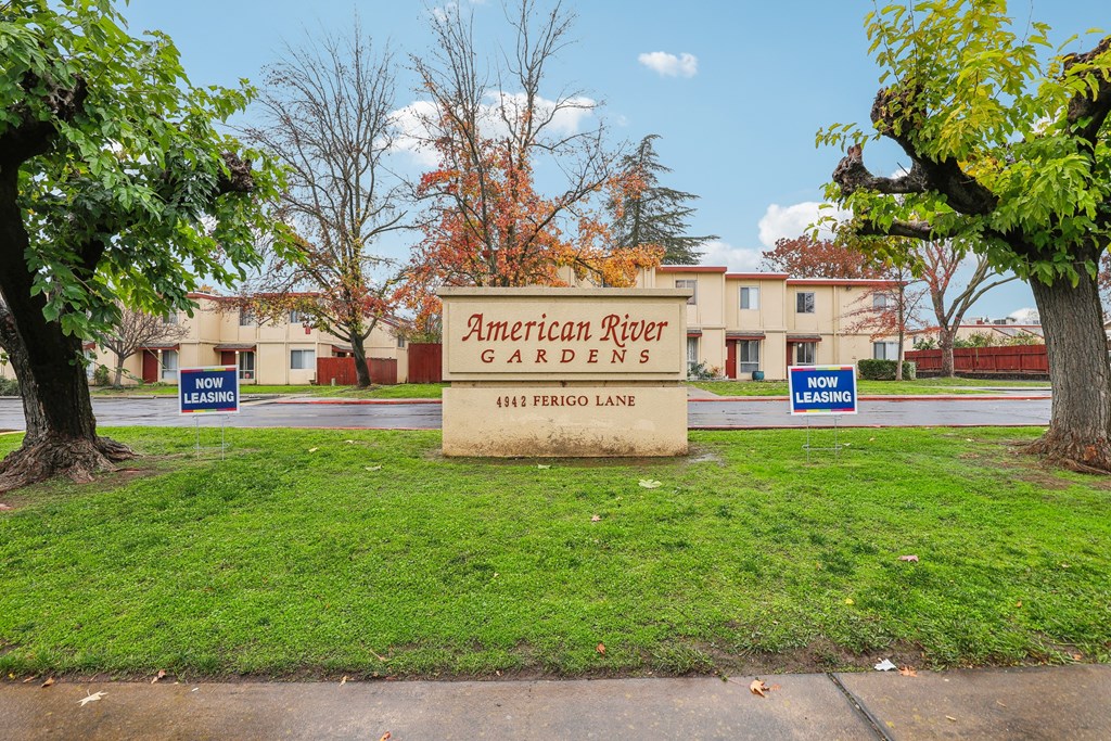 A sign for American River Gardens is displayed in front of a building.