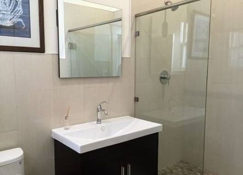 A bathroom with a sink, mirror, and shower.