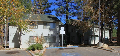 A white building with a green roof is surrounded by trees.