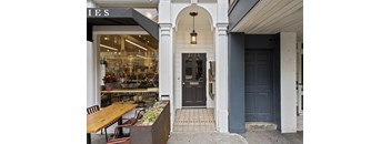 A storefront with a black door and a hanging light fixture.