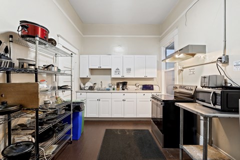 A kitchen with white cabinets and a black counter top.