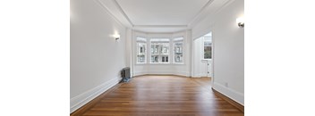 A long hallway with wood floors and white walls.