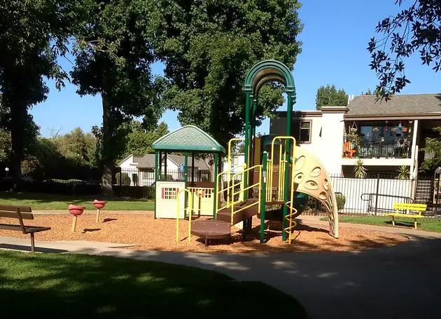 A playground with a green roofed structure and a yellow slide.