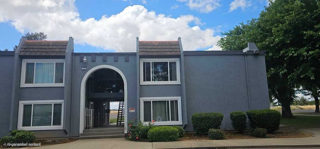 A grey building with a large arched entrance and staircase.