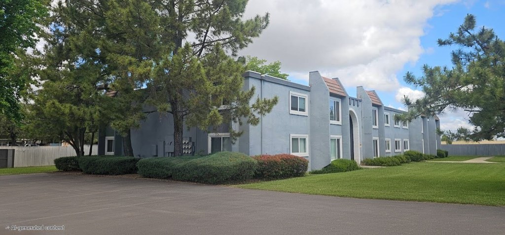 A multifamily housing building with trees in front.