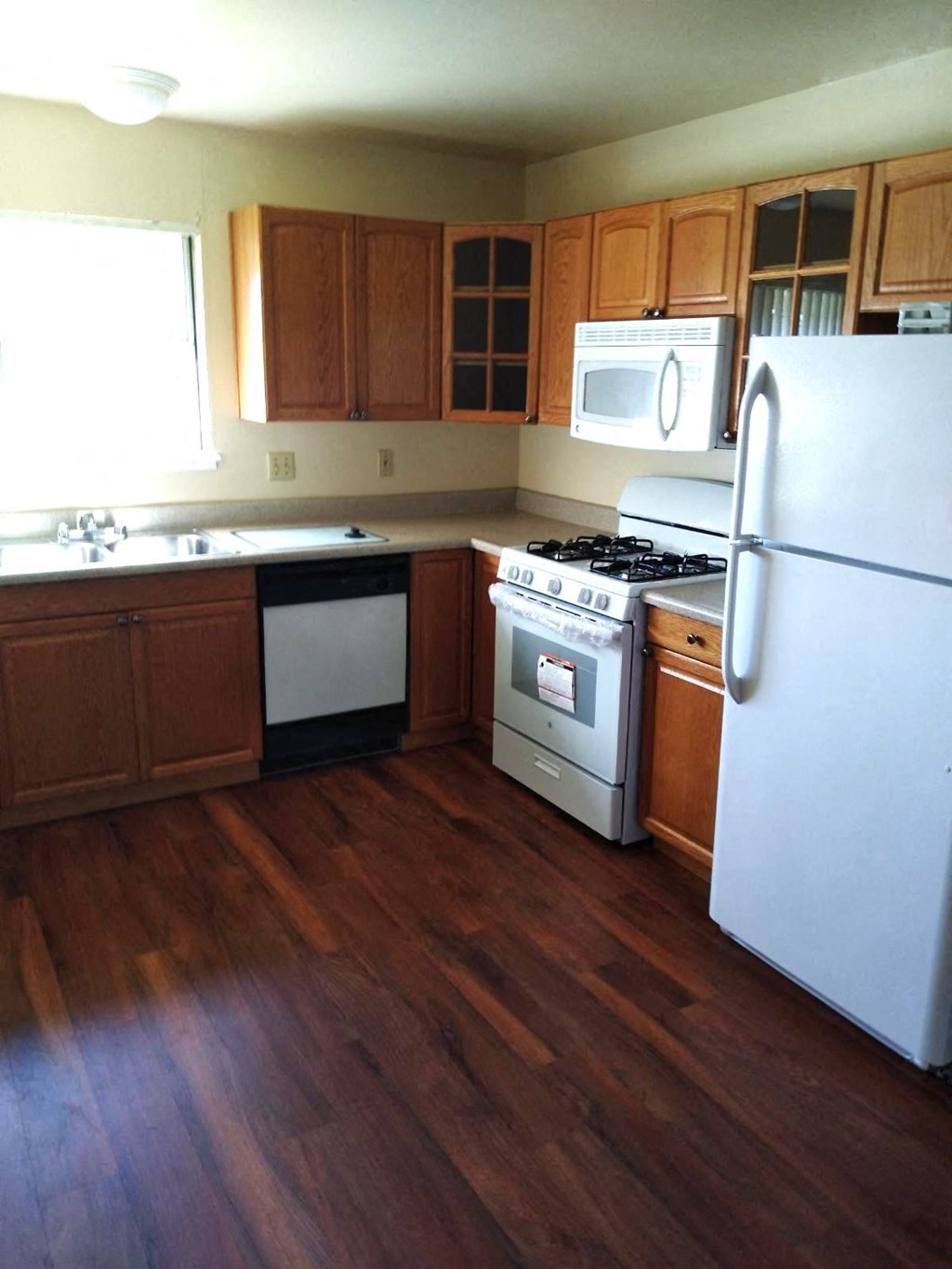 a kitchen with white appliances and wooden floors