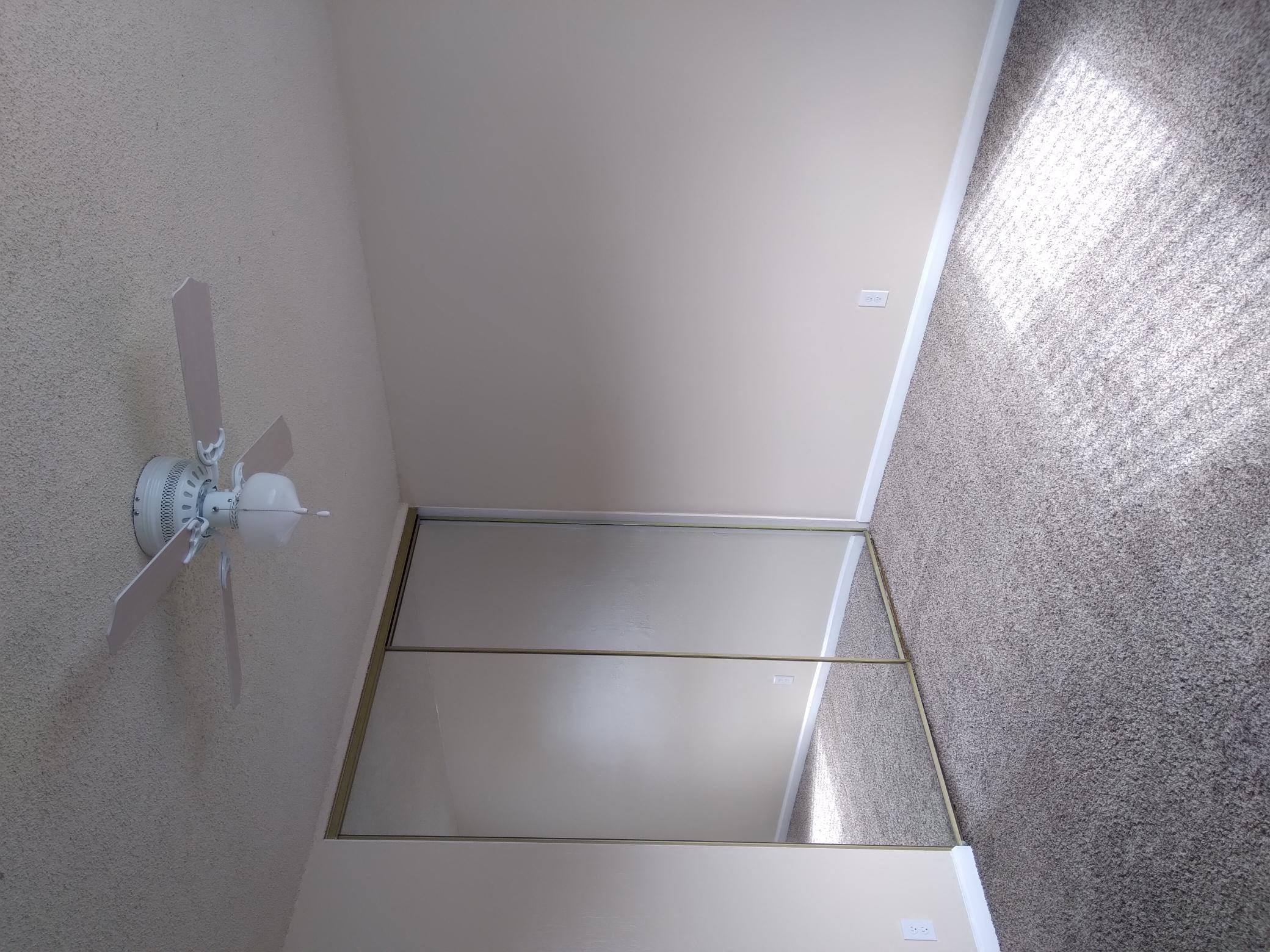 a ceiling fan in a bathroom with a mirrored closet