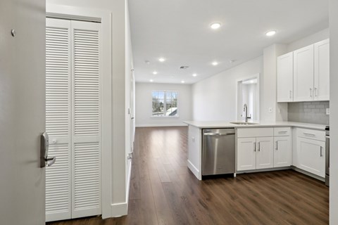 A kitchen with white cabinets and a wooden floor.