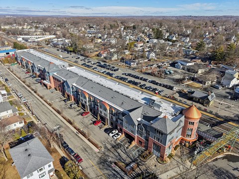 A large building with a red roof is surrounded by a parking lot.